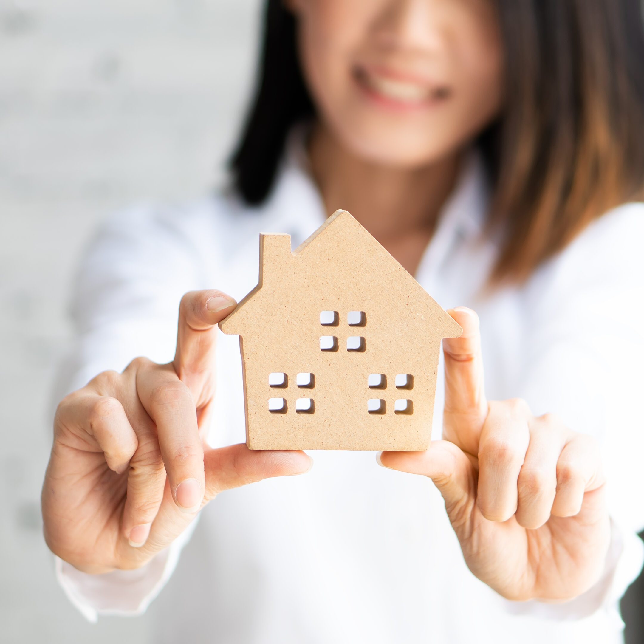 Woman holding a small wooden house model