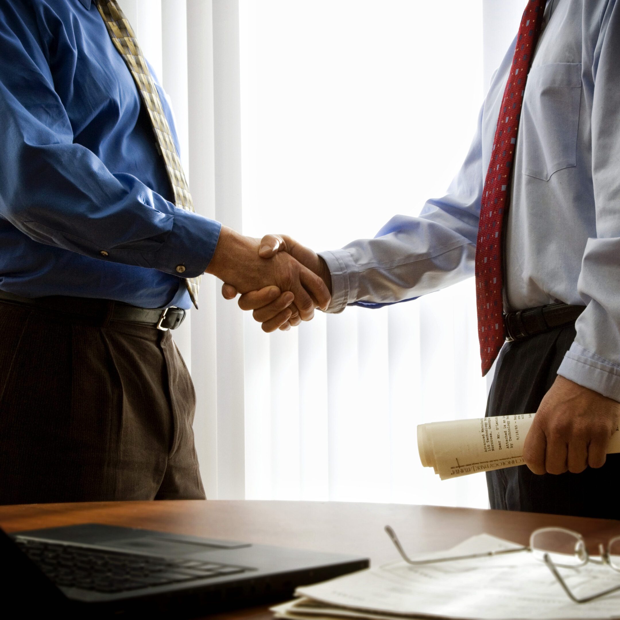 Two men in business attire handshake